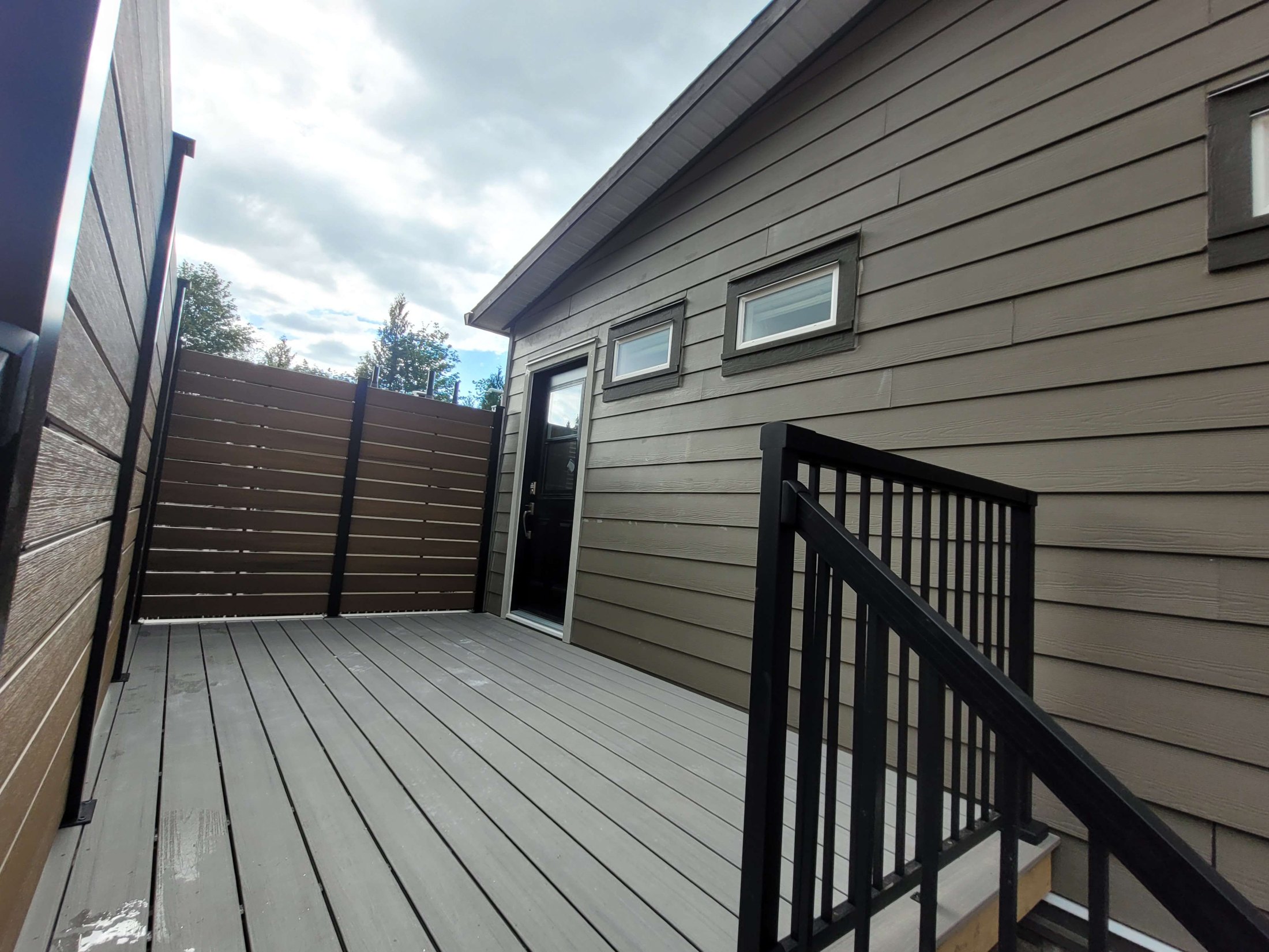 Finished Bedroom-to-Backyard composite deck with privacy screens and railing