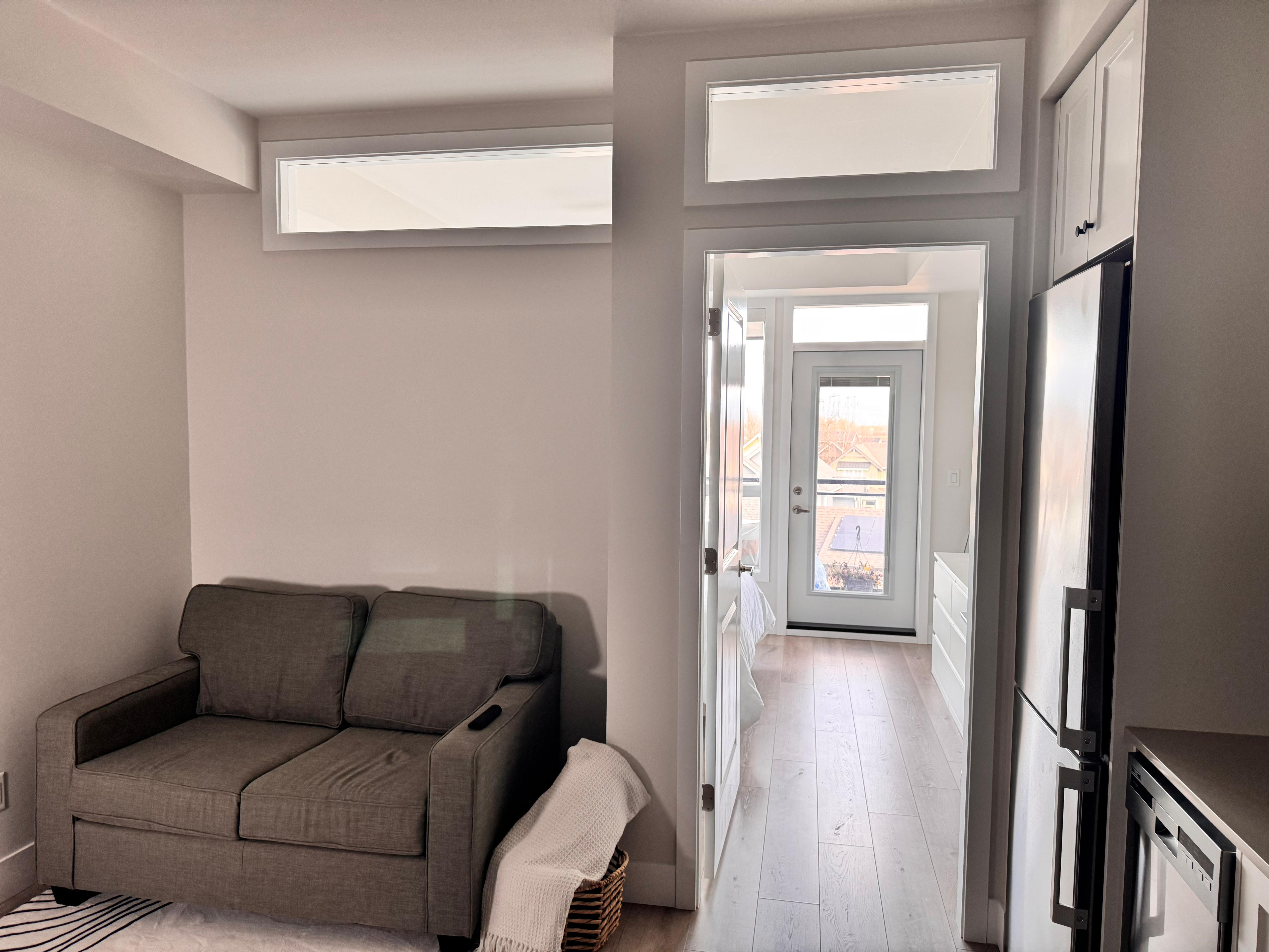Studio condo conversion with a separate bedroom, sofa recess, and glass above the partition